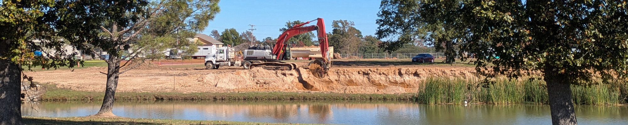 an excavator digging on pond expansion project